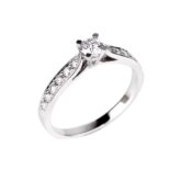 Bague en or blanc 18K avec diamant central de 0,20 carat et pavage de 12 diamants.
