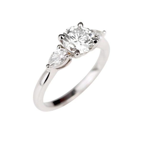 Bague en or blanc 18K avec diamant central rond de 1,06 carat encadré par deux diamants taille poire.