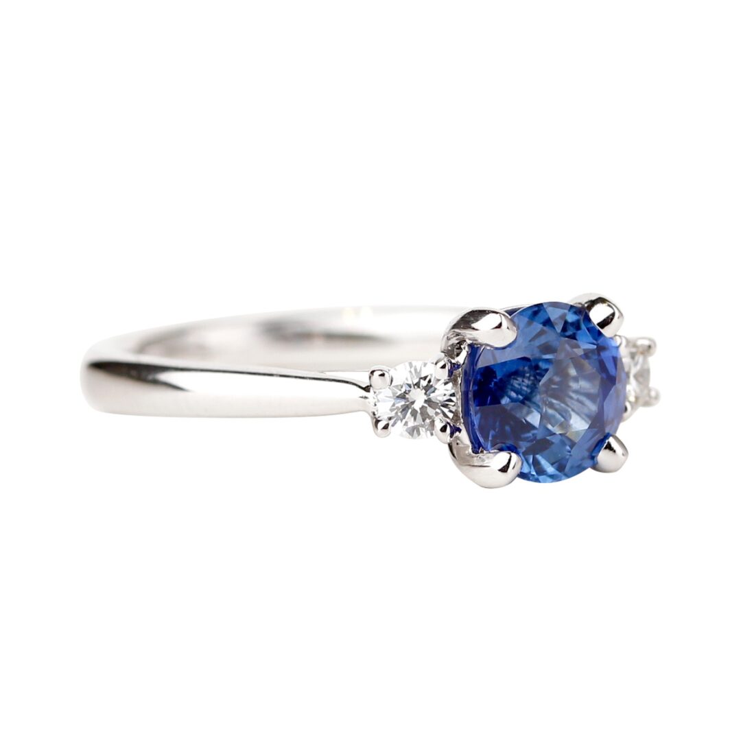 Bague saphir bleu accompagné de deux diamants ronds sur anneau en or blanc