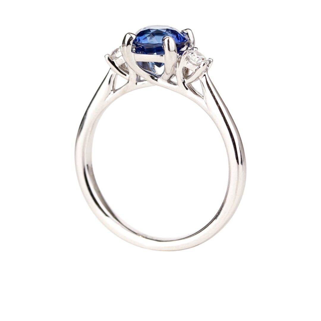 Bague saphir bleu accompagné de deux diamants ronds sur anneau en or blanc