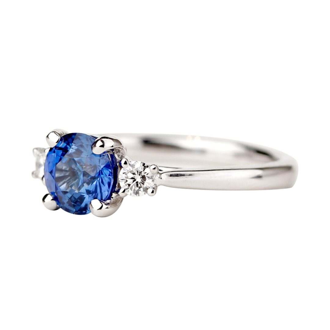 Bague saphir bleu accompagné de deux diamants ronds sur anneau en or blanc