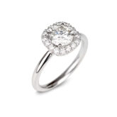 Bague de fiançailles en or blanc ornée d'un diamant central rond et d'un entourage de diamants.